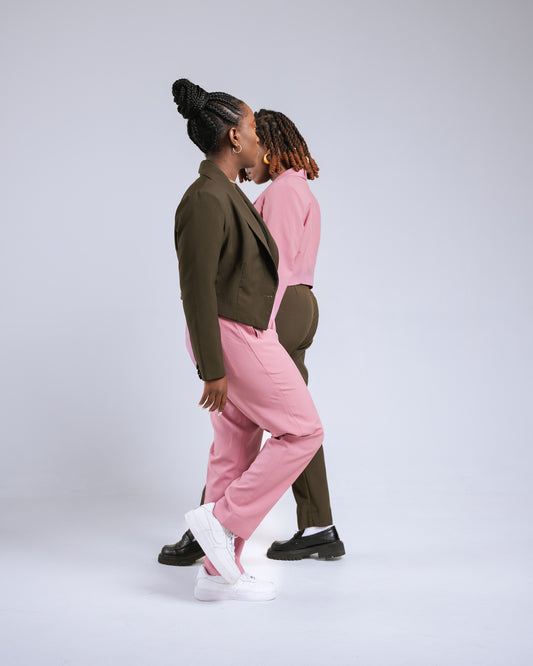 Two people wearing matching outfits of pink pants and green jackets on a white background