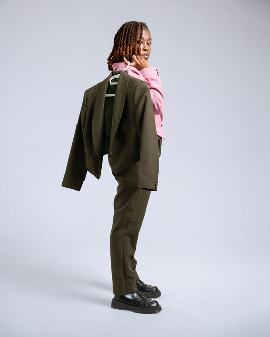Woman wearing a pink and green suit while holding a green coat on a white background
