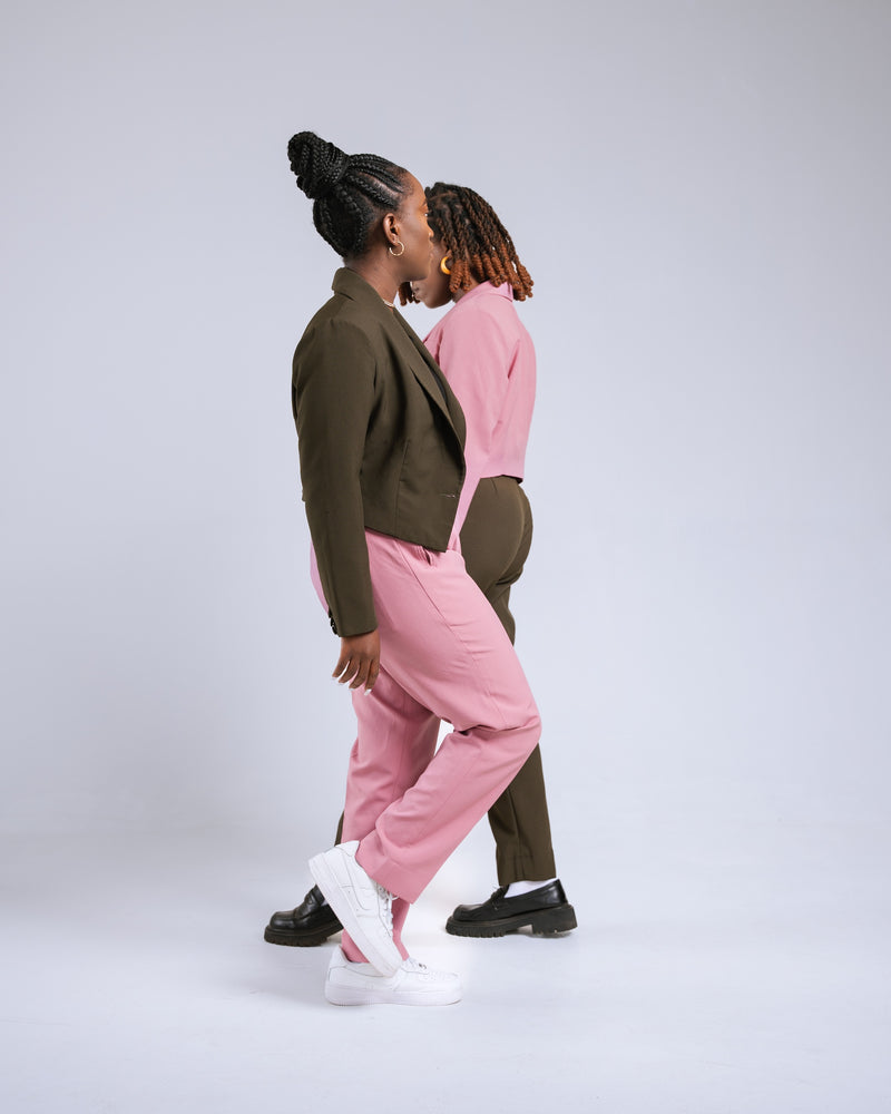 Two people wearing matching outfits of pink pants and green jackets on a white background